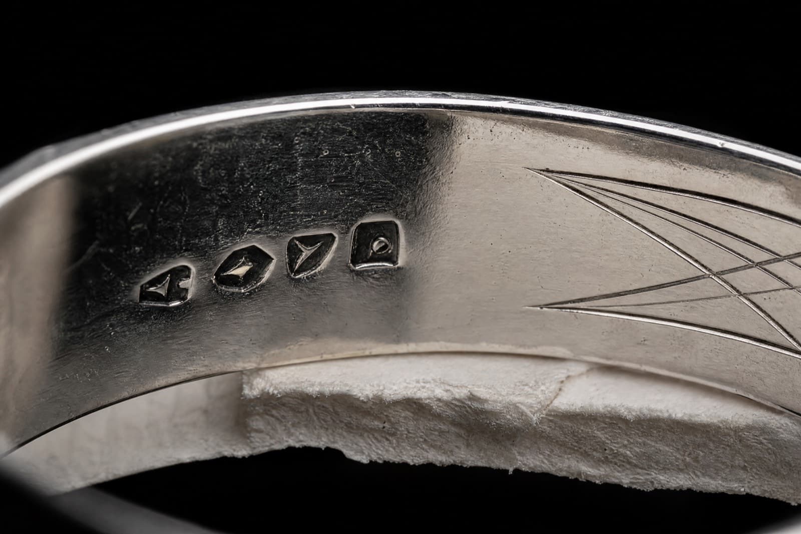 Struck punch marks inside a silver band with engraving beginning clear of them
