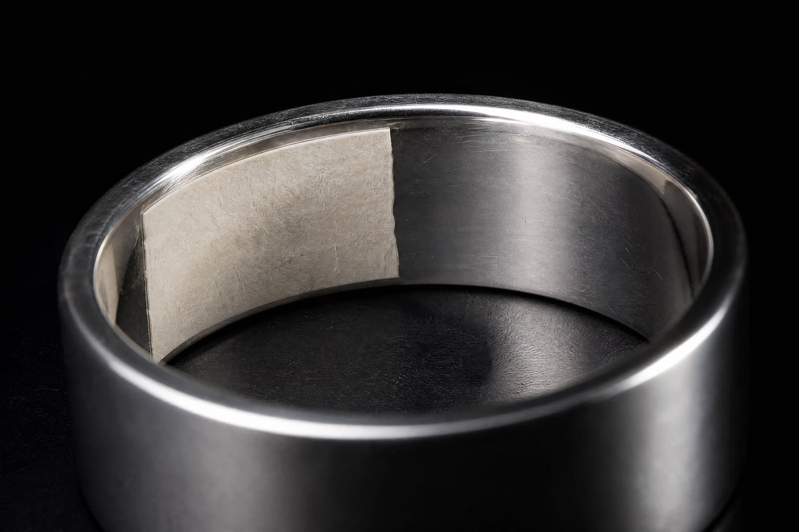 The inner wall of a silver band with a section masked off to keep it clear
