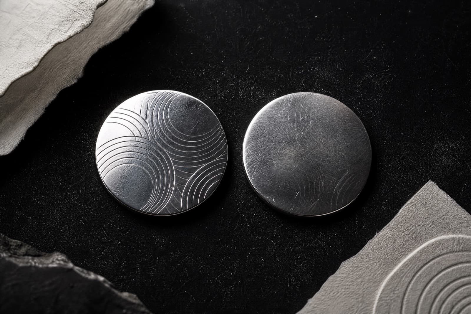 Two silver discs with the same pattern, one crisp and one worn smooth